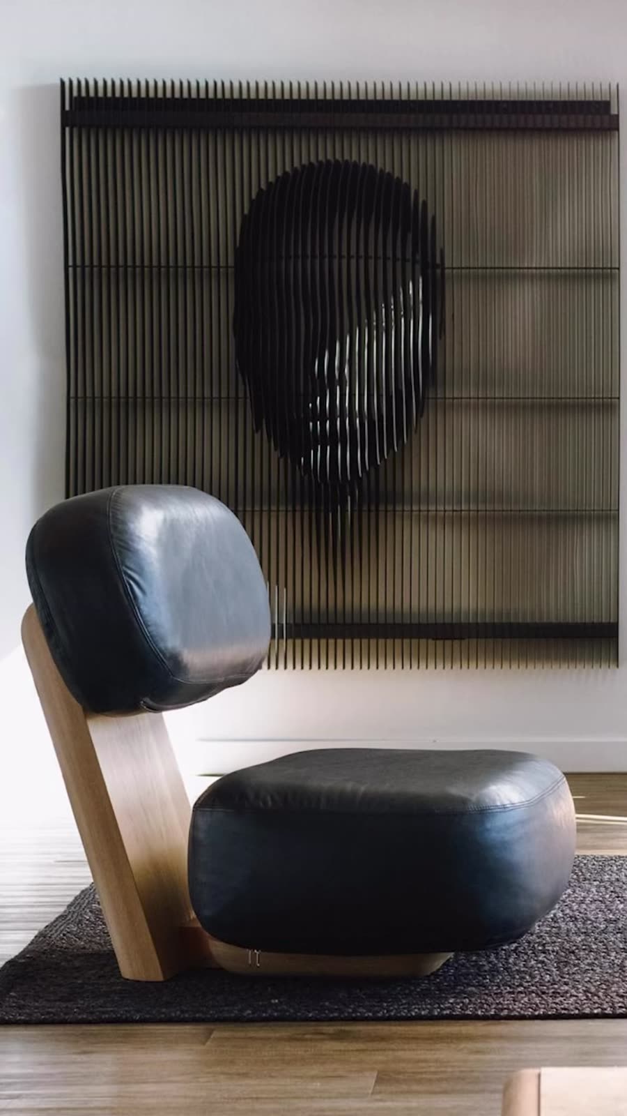 Occasional chair with black leather cushions on a timber frame, designed by the studio